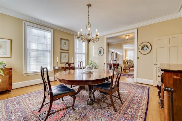 dining space with a notable chandelier, light hardwood / wood-style flooring, and ornamental molding