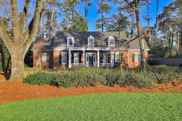 cape cod house featuring a front yard and covered porch