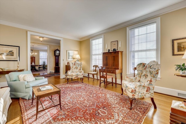 living room featuring ornamental molding, light wood-type flooring, and an inviting chandelier