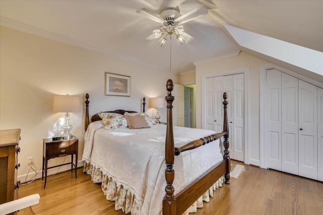 bedroom featuring hardwood / wood-style flooring, ceiling fan, ornamental molding, and two closets