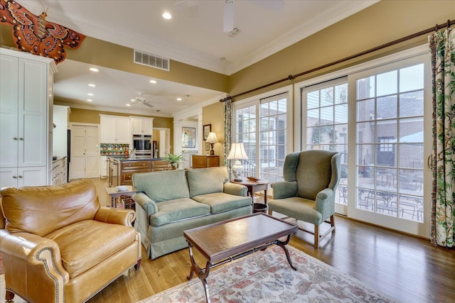 living room featuring ceiling fan, ornamental molding, and light hardwood / wood-style floors