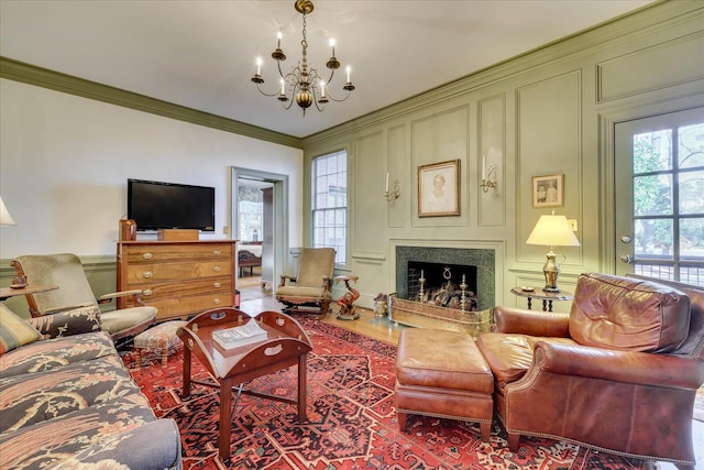 living room featuring crown molding, a premium fireplace, and a notable chandelier