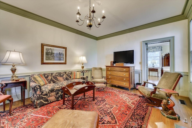 living room with hardwood / wood-style flooring, ornamental molding, and a chandelier