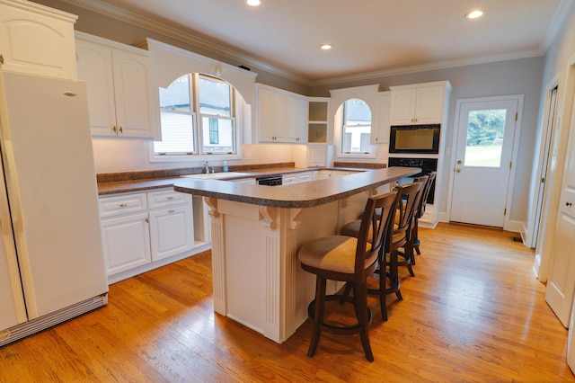 902 Patriots Pt, Mccormick, SC 29835 - kitchen featuring freestanding refrigerator, dark countertops, a breakfast bar area, oven, and white cabinetry