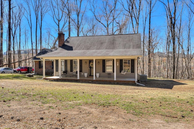 view of front of house featuring a porch, a chimney, and a front yard