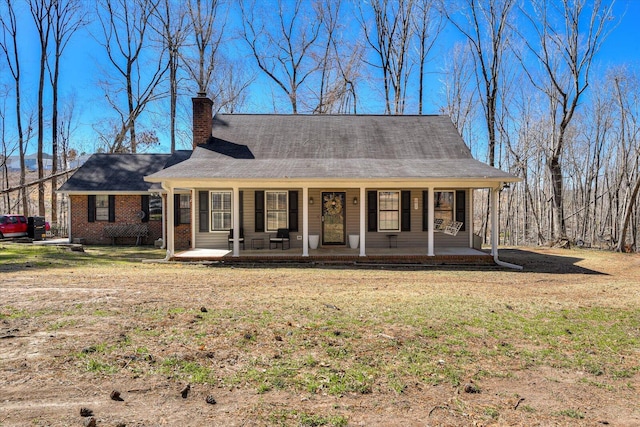 view of front facade featuring a porch, a chimney, a front lawn, and brick siding