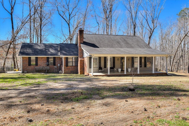 view of front of property featuring crawl space, covered porch, a chimney, and brick siding