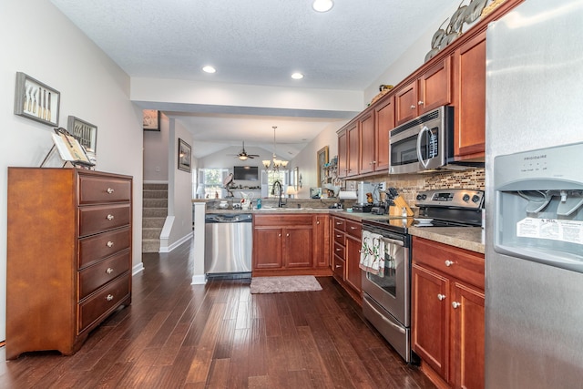 kitchen featuring kitchen peninsula, pendant lighting, lofted ceiling, decorative backsplash, and appliances with stainless steel finishes