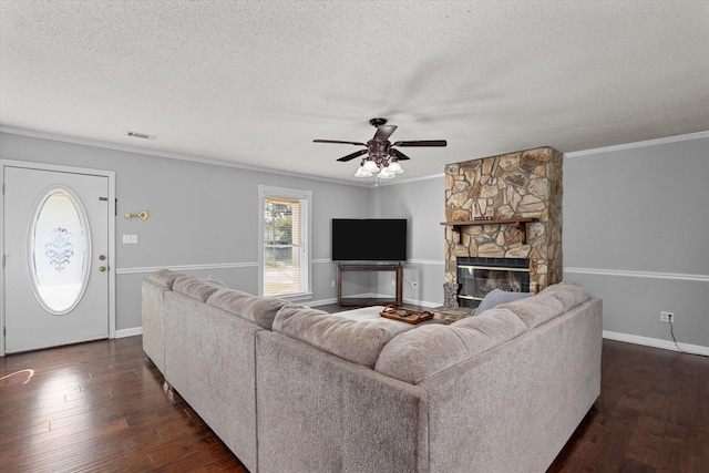 living room with crown molding, a fireplace, ceiling fan, and a textured ceiling