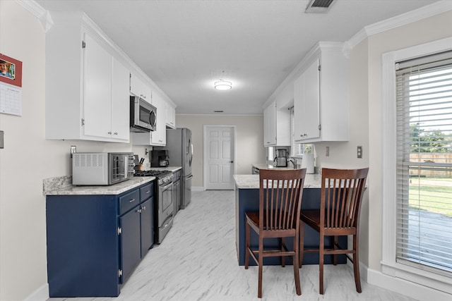 kitchen featuring plenty of natural light, white cabinetry, stainless steel appliances, and ornamental molding