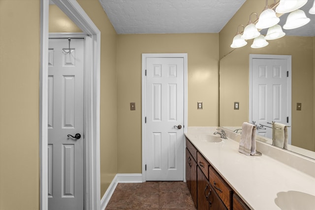 bathroom with vanity, a textured ceiling, and an inviting chandelier