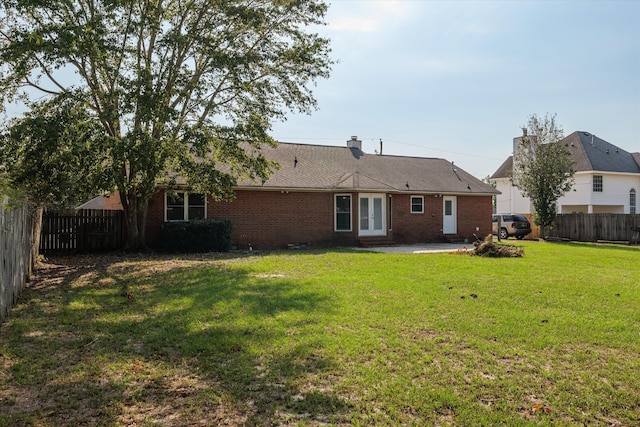 back of property with a lawn and french doors