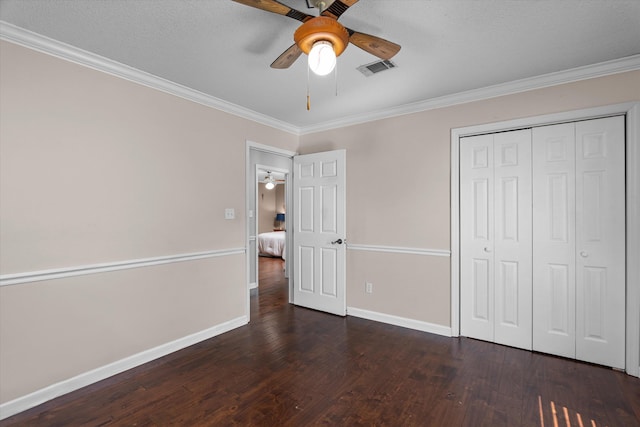 unfurnished bedroom with ceiling fan, dark hardwood / wood-style flooring, ornamental molding, and a closet