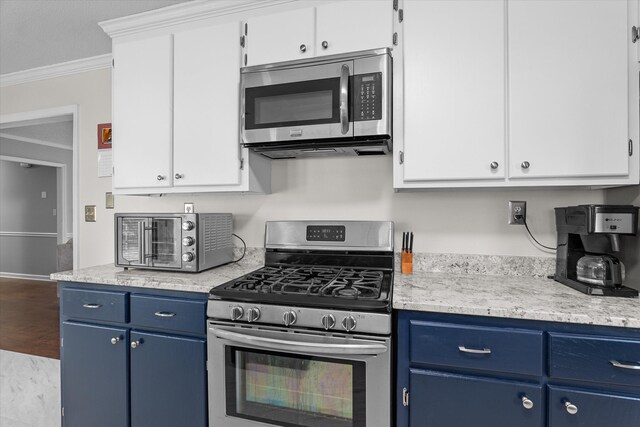 kitchen with white cabinets, appliances with stainless steel finishes, blue cabinets, and ornamental molding