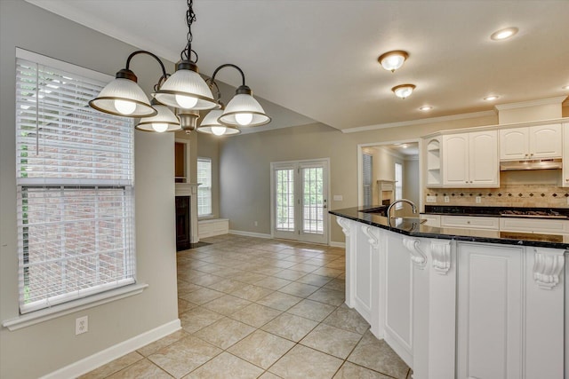 1123 Blackfoot Dr, Evans, GA 30809 - kitchen featuring under cabinet range hood, light tile patterned floors, ornamental molding, stovetop, and decorative backsplash