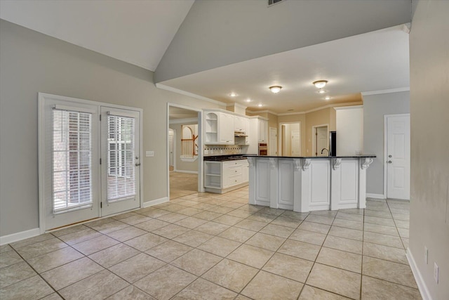 1123 Blackfoot Dr, Evans, GA 30809 - kitchen featuring dark countertops, open shelves, crown molding, light tile patterned floors, and a kitchen breakfast bar