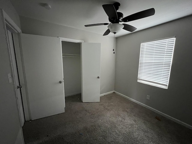 unfurnished bedroom with dark colored carpet, a closet, and ceiling fan