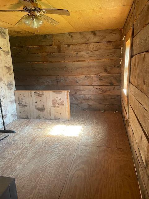 unfurnished room featuring ceiling fan and wood walls