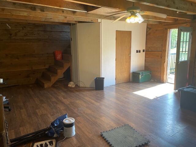 interior space featuring wood-type flooring, ceiling fan, and wood walls