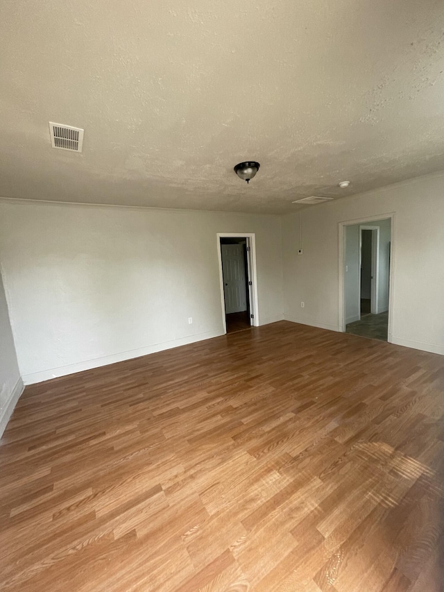 unfurnished room with a textured ceiling and light hardwood / wood-style flooring