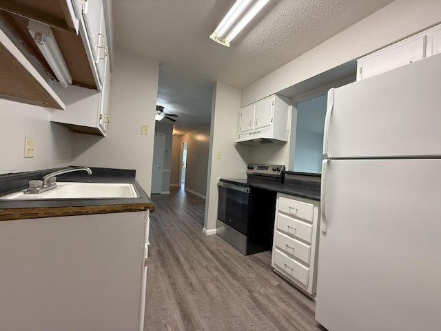 1017 Stevens Creek Rd, Augusta, GA 30907 - kitchen with freestanding refrigerator, stainless steel electric stove, under cabinet range hood, dark countertops, and white cabinetry