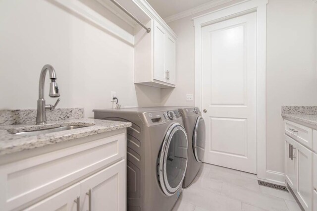 clothes washing area with cabinets, sink, washing machine and dryer, light tile patterned floors, and ornamental molding