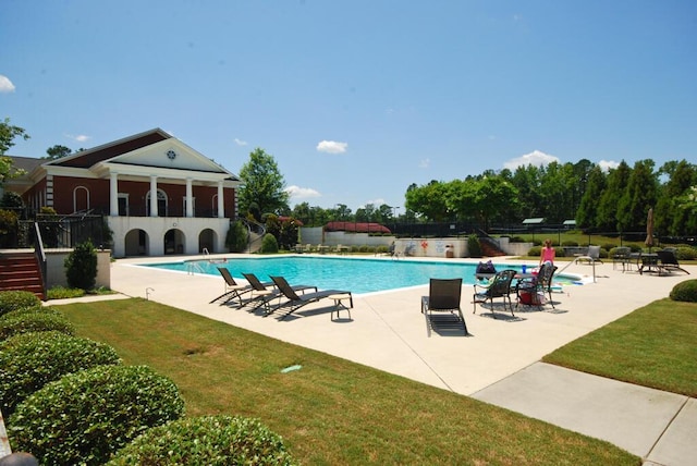 view of pool with a patio and a lawn