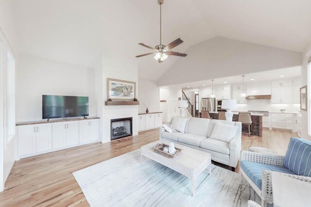 living room featuring ceiling fan, light hardwood / wood-style flooring, and high vaulted ceiling