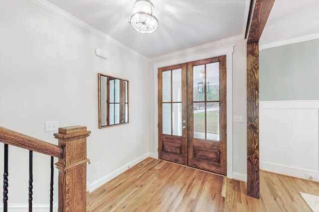 entryway with light hardwood / wood-style floors, ornamental molding, and french doors