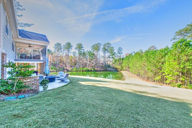 view of yard featuring ceiling fan, a water view, and a patio