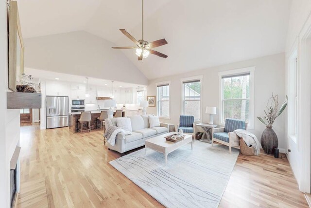 living room featuring ceiling fan, light hardwood / wood-style flooring, and high vaulted ceiling