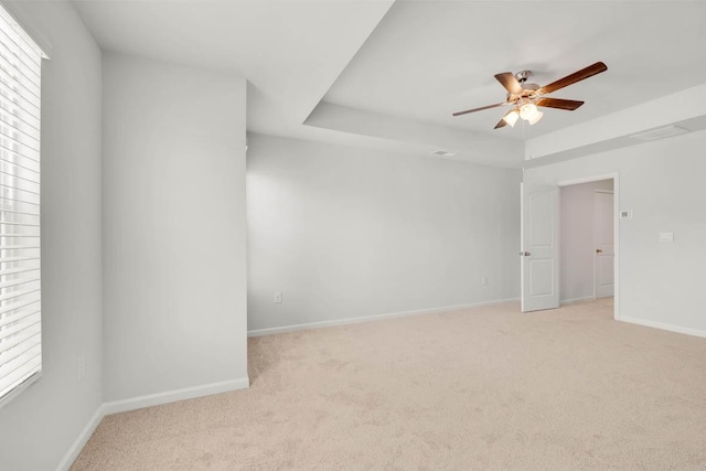 carpeted spare room featuring a tray ceiling and ceiling fan