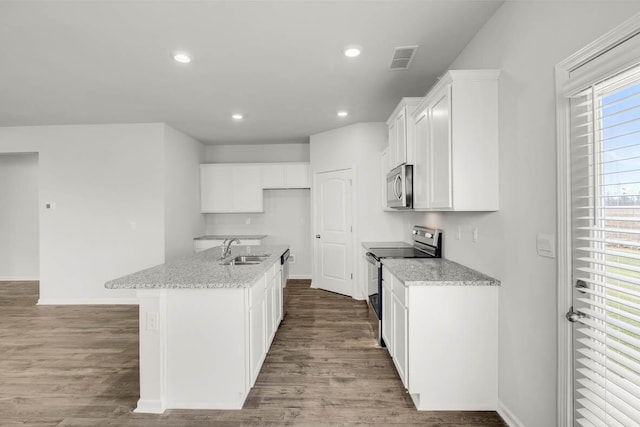 kitchen with light stone countertops, appliances with stainless steel finishes, sink, white cabinets, and an island with sink