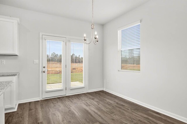 unfurnished dining area featuring a chandelier and hardwood / wood-style flooring