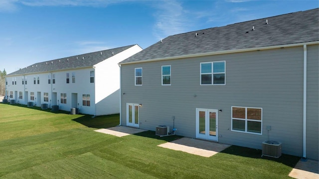 back of property with french doors, central air condition unit, and a lawn