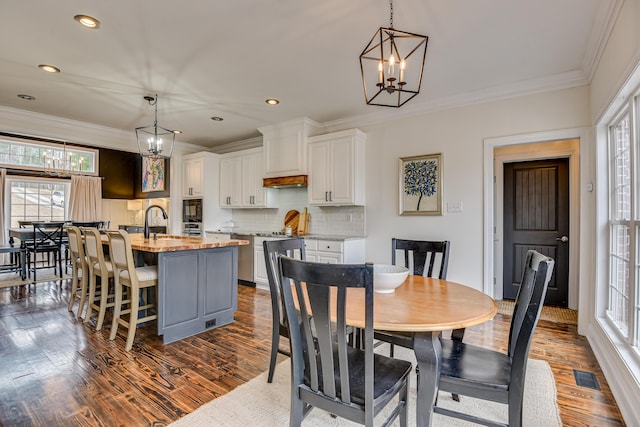 dining room featuring a notable chandelier, dark hardwood / wood-style flooring, ornamental molding, and sink