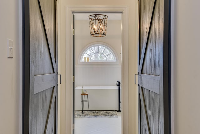 entryway with tile patterned floors, a notable chandelier, and a barn door