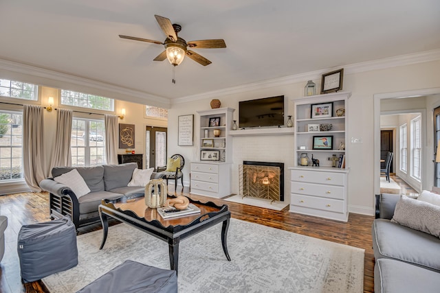 living room with hardwood / wood-style flooring, a brick fireplace, ceiling fan, and ornamental molding