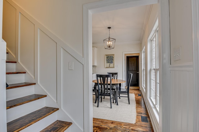 dining space featuring dark wood-type flooring, an inviting chandelier, and crown molding