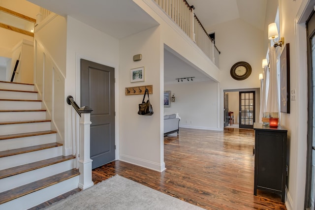 entrance foyer with dark hardwood / wood-style flooring and a towering ceiling