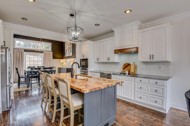 kitchen with black appliances, wood counters, white cabinetry, and an island with sink