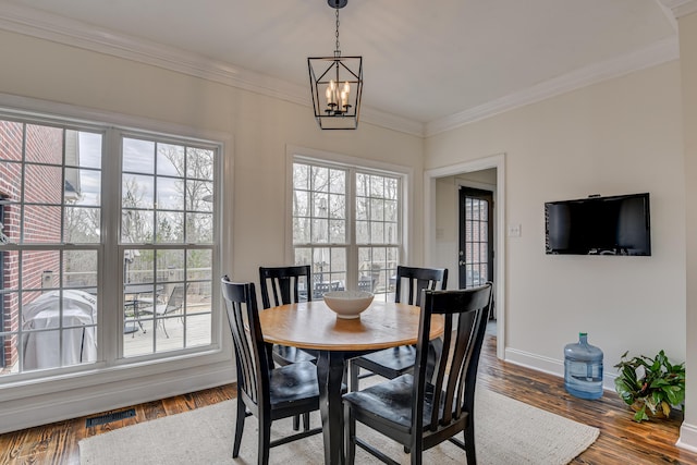 dining room with plenty of natural light, wood-type flooring, a chandelier, and ornamental molding