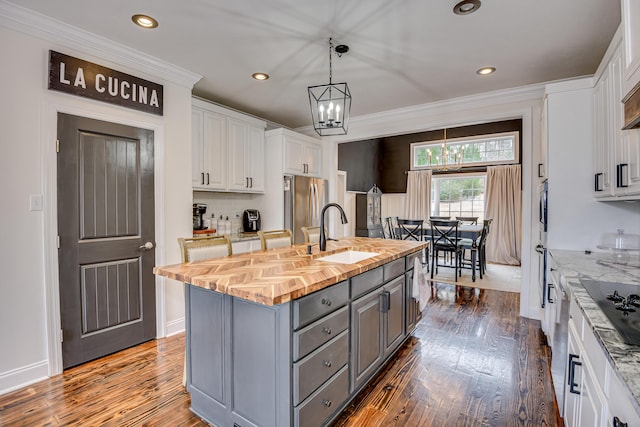 kitchen featuring a center island with sink, sink, gray cabinets, stainless steel fridge, and white cabinetry