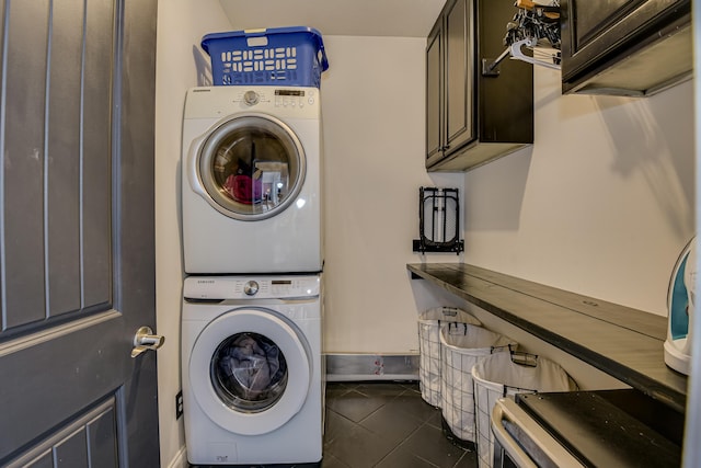 laundry area with dark tile patterned floors and stacked washer and clothes dryer