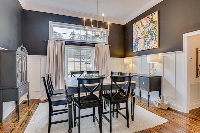 dining space with crown molding, a notable chandelier, and hardwood / wood-style flooring