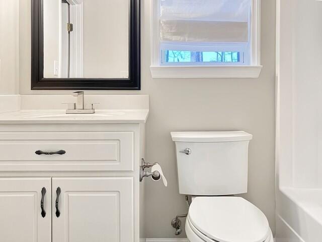 bathroom featuring toilet, baseboards, a bath, and vanity