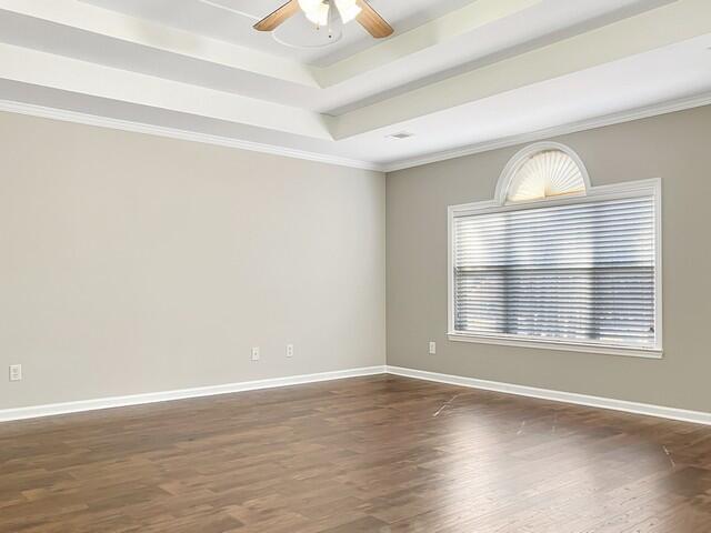 unfurnished room with dark wood-style floors, a tray ceiling, ceiling fan, and baseboards