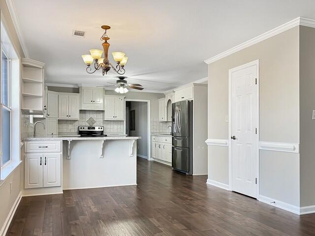 kitchen featuring a peninsula, stainless steel appliances, visible vents, light countertops, and a kitchen bar