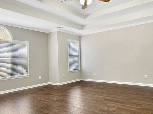 unfurnished room with a healthy amount of sunlight, baseboards, a raised ceiling, and dark wood-style flooring