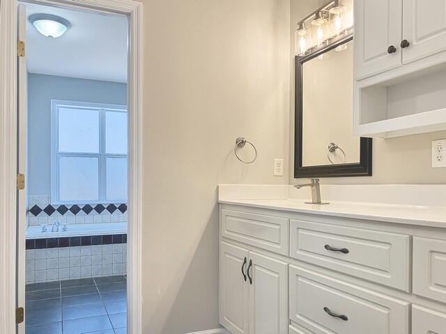 full bath featuring a relaxing tiled tub, tile patterned floors, and vanity